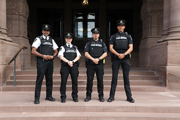 four uniformed officers standing in front of the main Legislative Building
