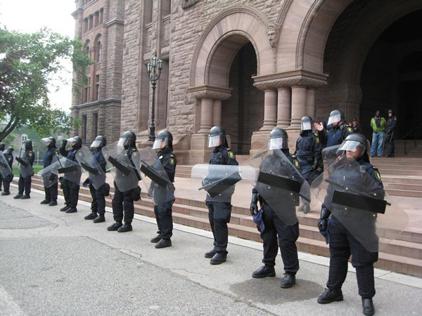 officers wearing protective gear standing next to each other in front of the Legislative Building
