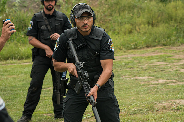 two Legislative Protective Service officers standing on grass wearing noise protection earmuffs and holding weapons