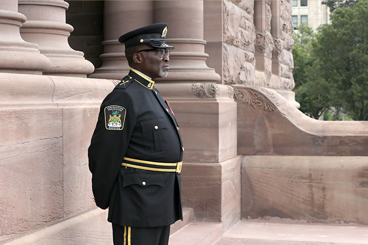 officer standing outside of Legislative Building in ceremonial uniform