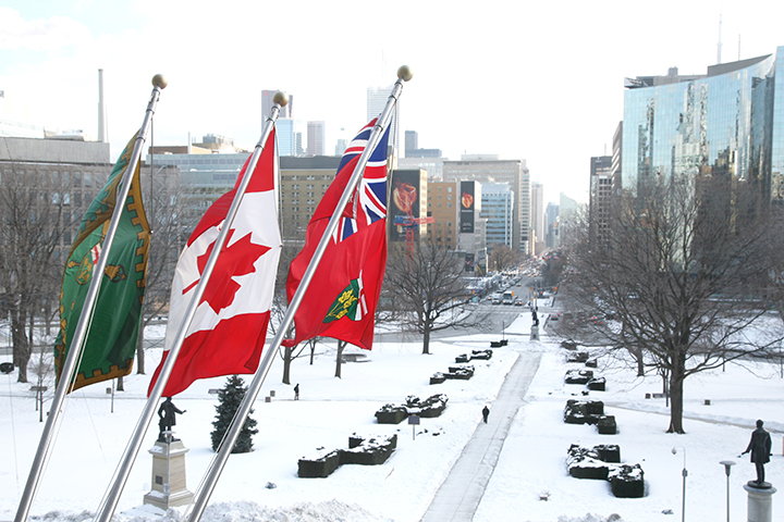 flags for the Legislative Assembly of Ontario, Canada, and Ontario, flying over snow-covered legislative grounds