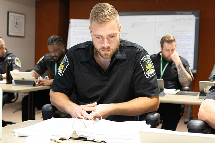 Legislative Protective Service officer seated at desk looking at binder